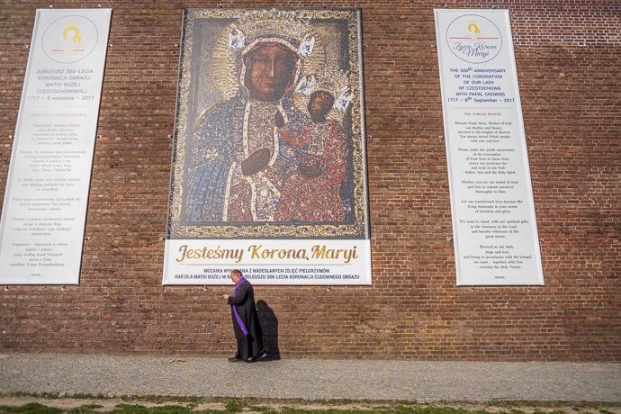 A priest walks along a fortress wall on which banners have been hung. Image: Michel Meijer