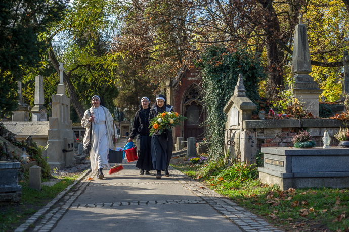 Three nuns armed with cleaning equipment and flowers walk across the cemetery, All Saints' Day in Poland. Image: Michel Meijer