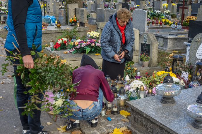 A family lays flowers and places candles on a grave, All Saints' Day in Poland. Image: Michel Meijer
