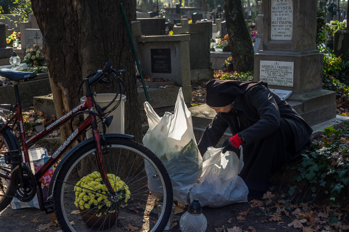 A nun cleans a grave and sets flowers on it, All Saints' Day in Poland. Image: Michel Meijer