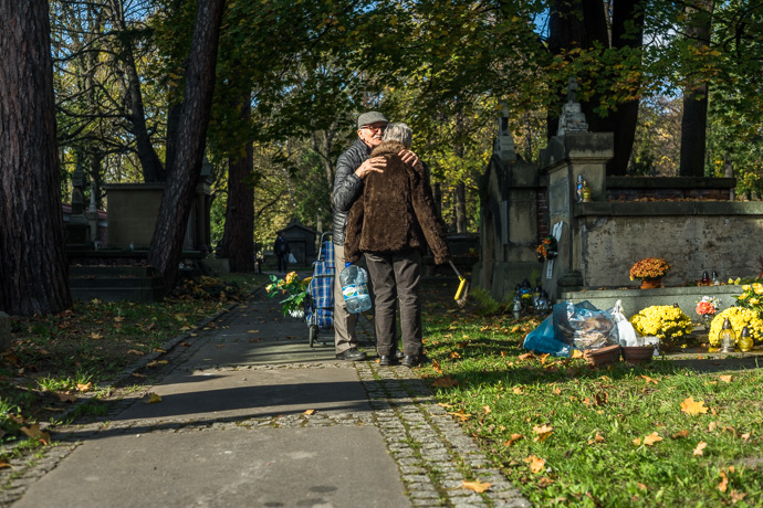 A man embraces a woman who is cleaning a grave, All Saints' Day in Poland. Image: Michel Meijer