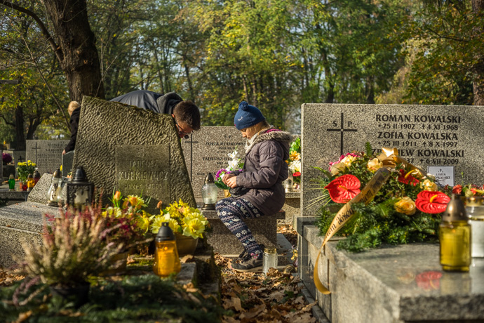 Father and daughter clean a grave and place candles on it, All Saints' Day in Poland. Image: Michel Meijer