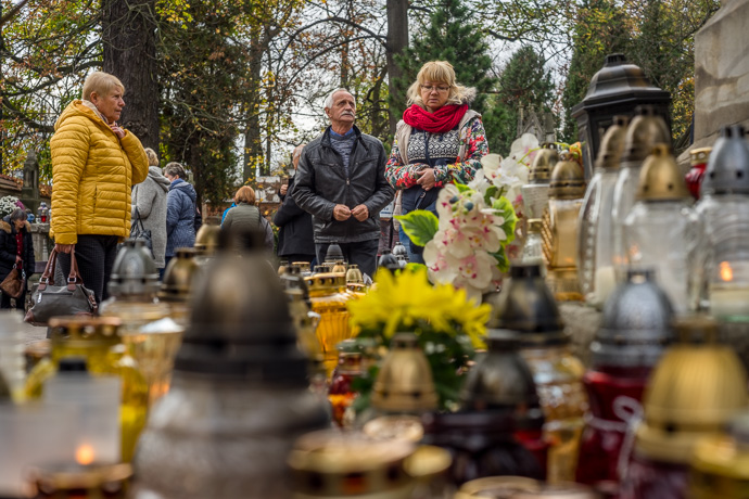 People stop at a monument under which hundreds of candles are placed, All Saints' Day in Poland. Image Michel Meijer