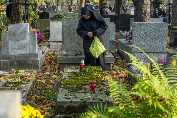 A nun stands praying in front of a tombstone in the cemetery, All Saints' Day in Poland. Image: Michel Meijer