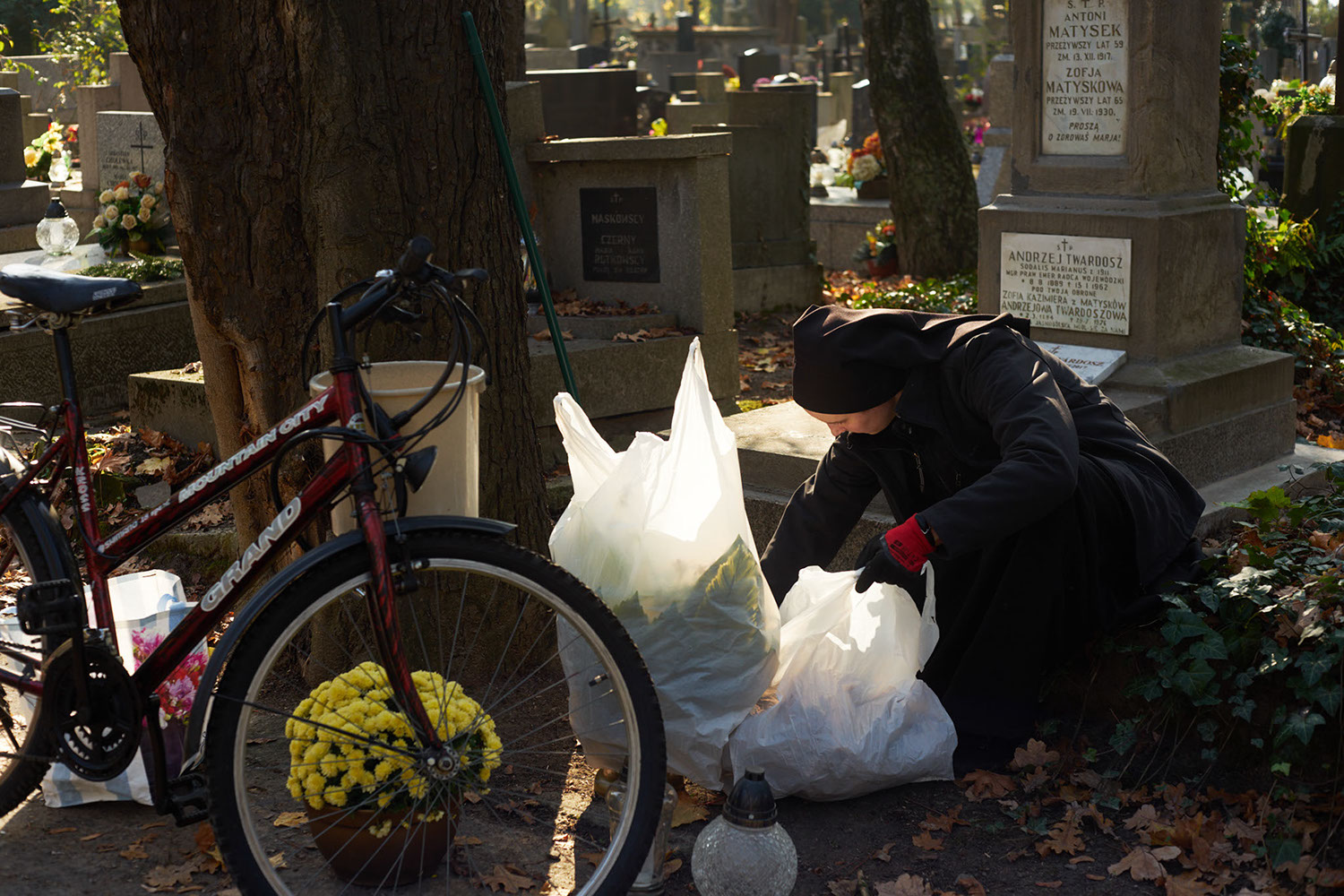 A nun takes care of a grave with flowers and candles in Rakowicki cemetery in Krakow, Poland in 2019 - image: Michel Meijer