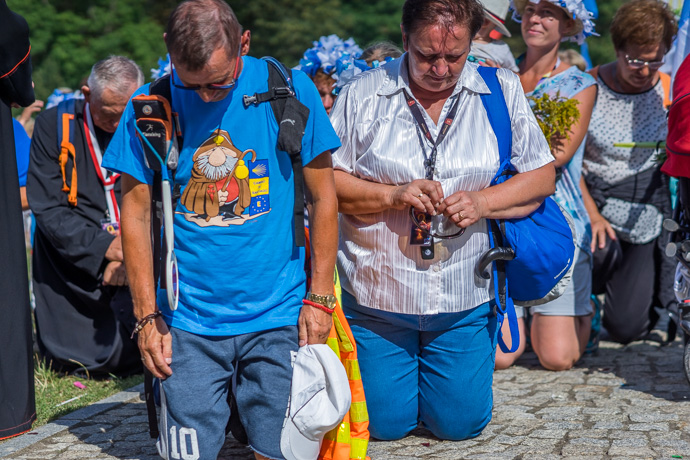 A group of pilgrims kneels and prays in front of the Jasna Góra pilgrimage site.