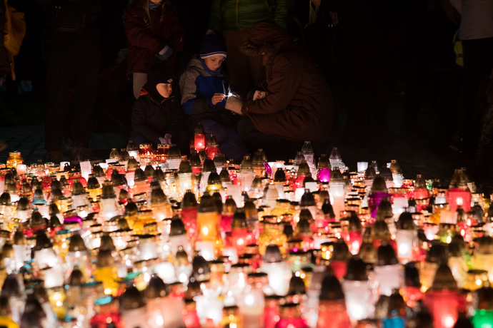 A child lights a candle under the direction of his mother, All Saints' Day in Poland. Image: Michel Meijer