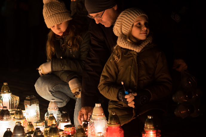 A father and his two daughters light a candle, All Saints' Day in Poland.  Image: Michel Meijer