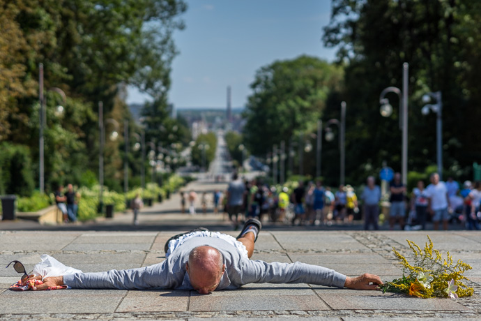 A pilgrim lies on the ground and prays in front of the Jasna Góra pilgrimage site. Image: Michel Meijer