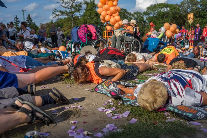 A group of pilgrims lie on the ground and pray in front of the Jasna Góra pilgrimage site. Image: Michel Meijer