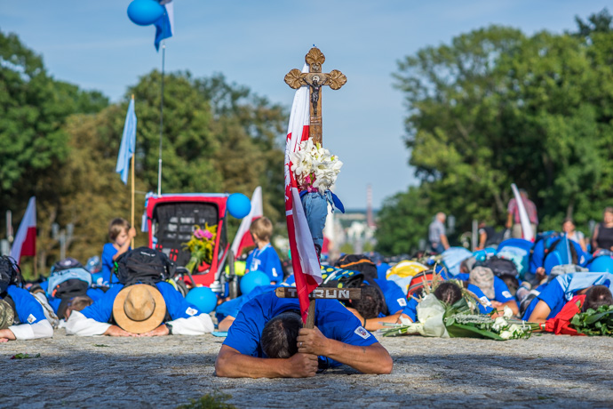 A group of pilgrims lie on the ground and pray in front of the Jasna Góra pilgrimage site. Image: Michel Meijer