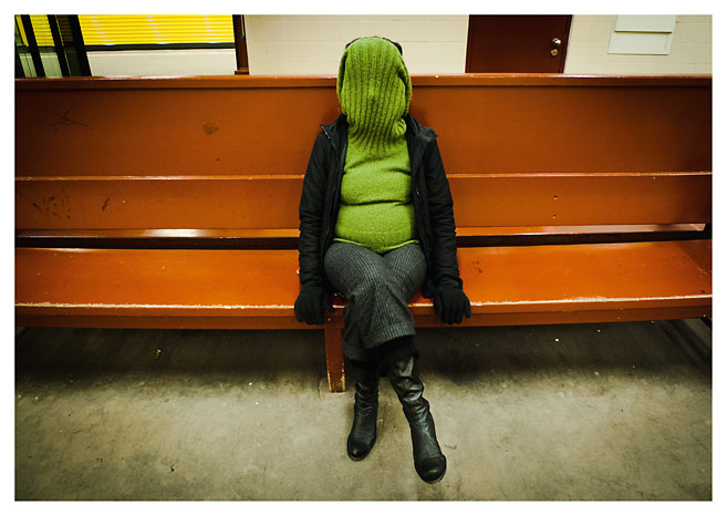 Eine Frau mit verdecktem Gesicht sitzt auf einer Bank in einem Berliner U-Bahnhof. Das Foto wurde von Christian Reister aufgenommen.