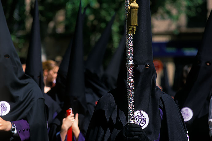 Hooded penitents stand in the blazing sun, waiting for the procession to proceed. Image: Michel Meijer