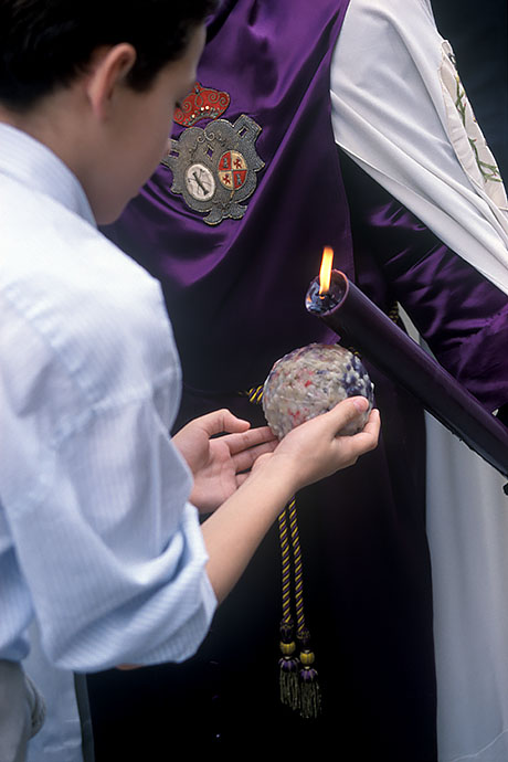 A boy collects candle wax from the candles that the penitents carry with them during the procession. Image: Michel Meijer